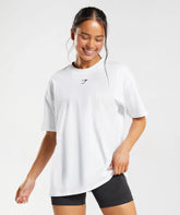 وصف: امرأة ترتدي تي شيرت "Fraction Oversize" من "Gymshark | United We Sweat" وشورت أسود.
